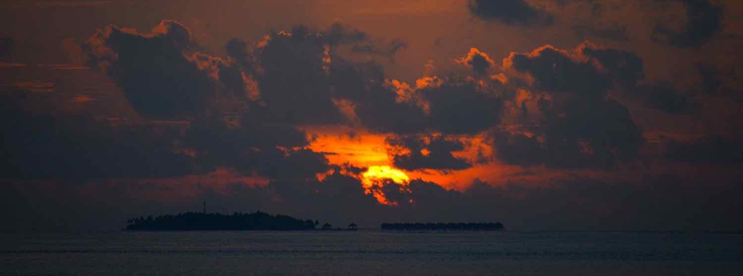 Sunset behind Vilamendhoo Island and its overwater villas, South Ari Atoll